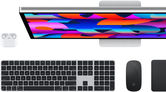 Imagem de cima do monitor Studio Display, Magic Keyboard preto, Magic Mouse preto, Magic Trackpad preto e estojo de recarga dos AirPods brancos