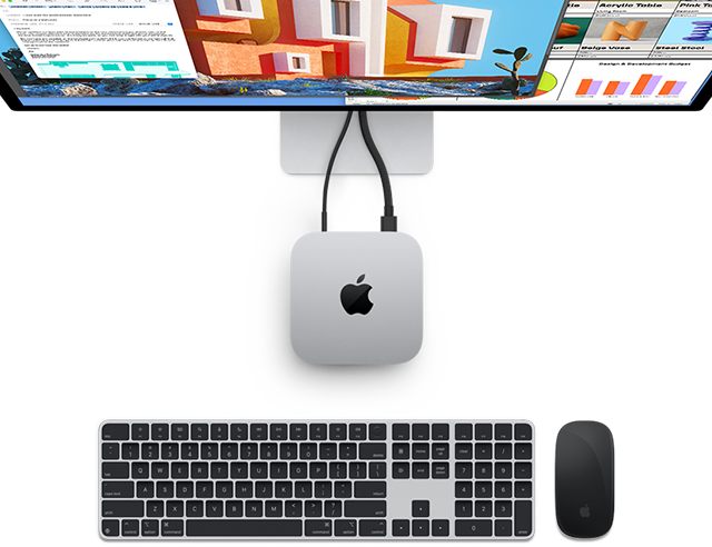 Parte superior do Mac mini prateado com logotipo da Apple, conectado a um monitor e ao lado de um Magic Keyboard e Magic Mouse sem fio.
